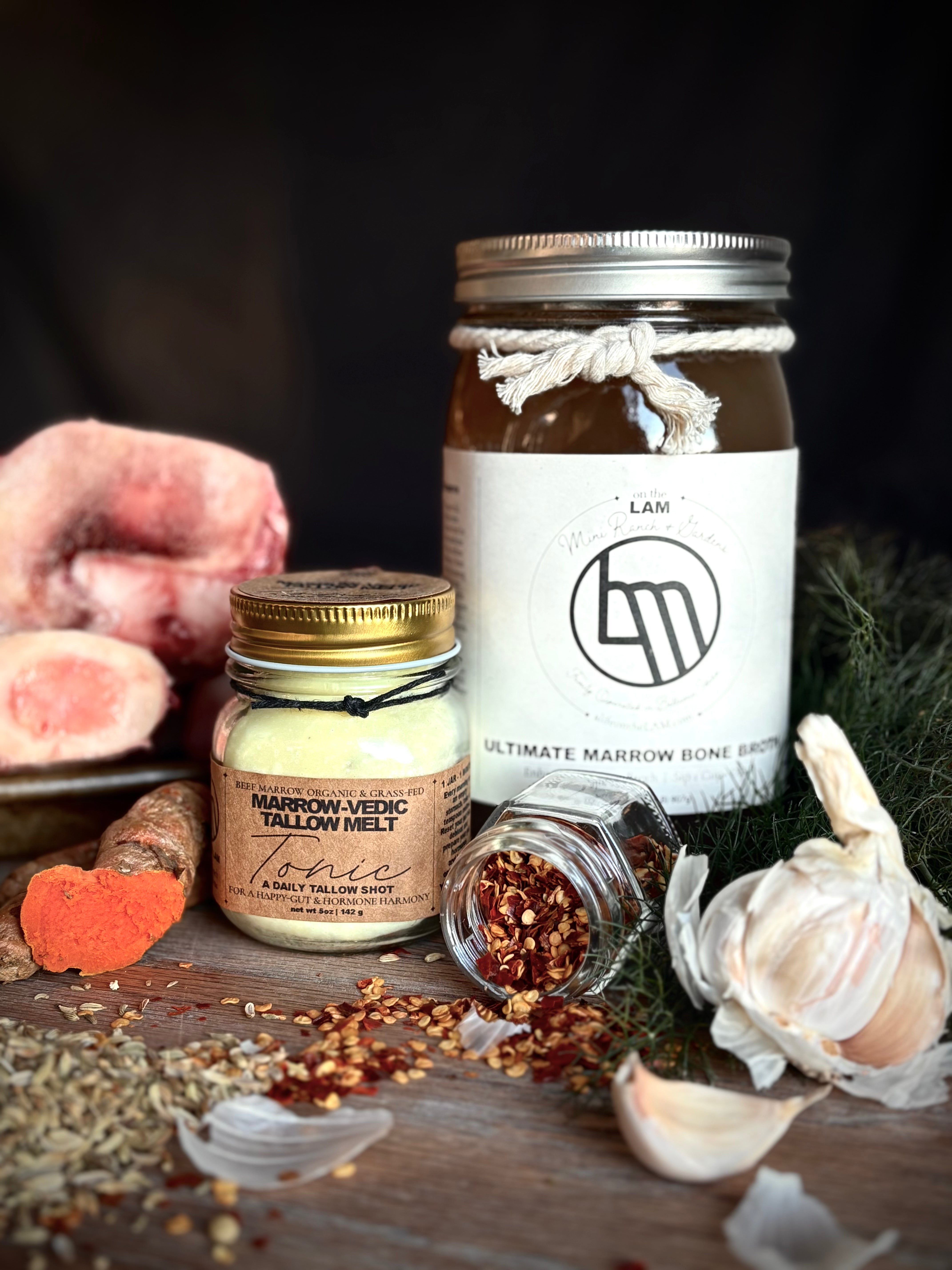 Two jars, organic bone broth and beef tallow on a wooden surface with ingredients around them.